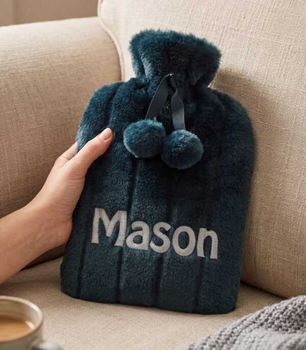 Charcoal fluffy personalised hot water bottle embroidered with Mason, shown on a sofa