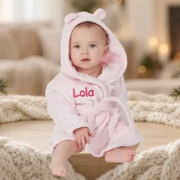 Baby in a pink personalised hooded robe embroidered with Lola