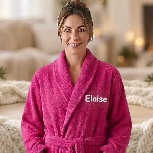 Woman in a fuchsia personalised towelling robe embroidered with Eloise