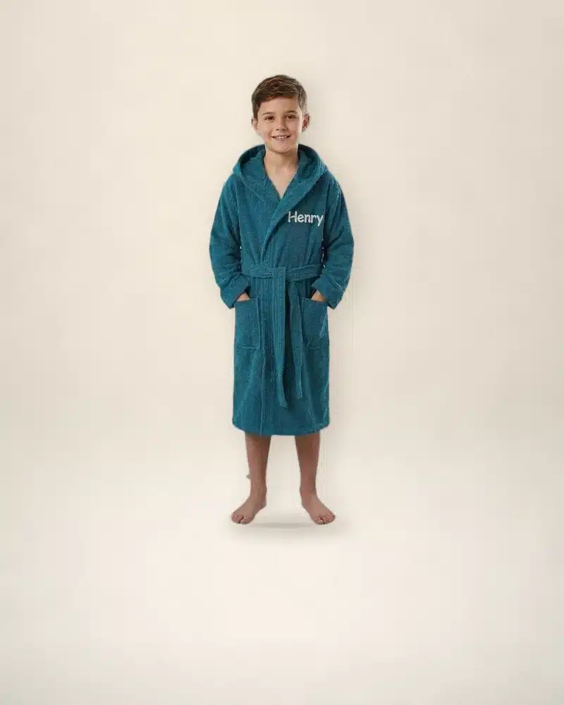 Boy in a teal personalised kids towelling robe embroidered with his name