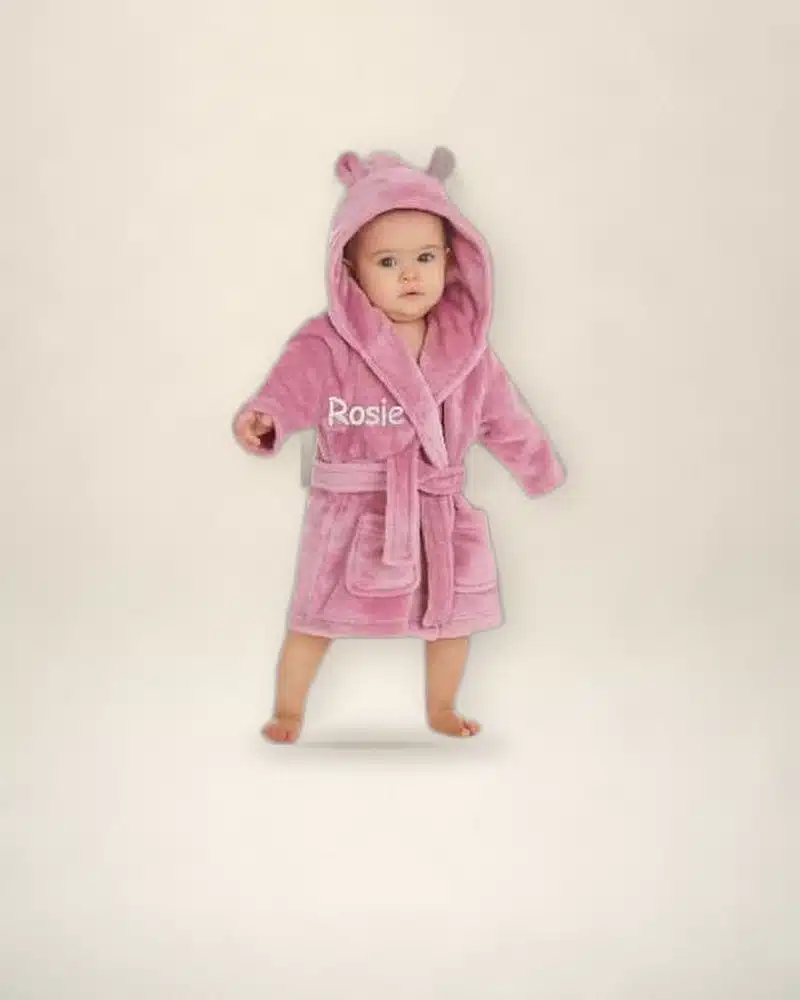 Baby in a dusky pink personalised hooded robe embroidered with Rosie