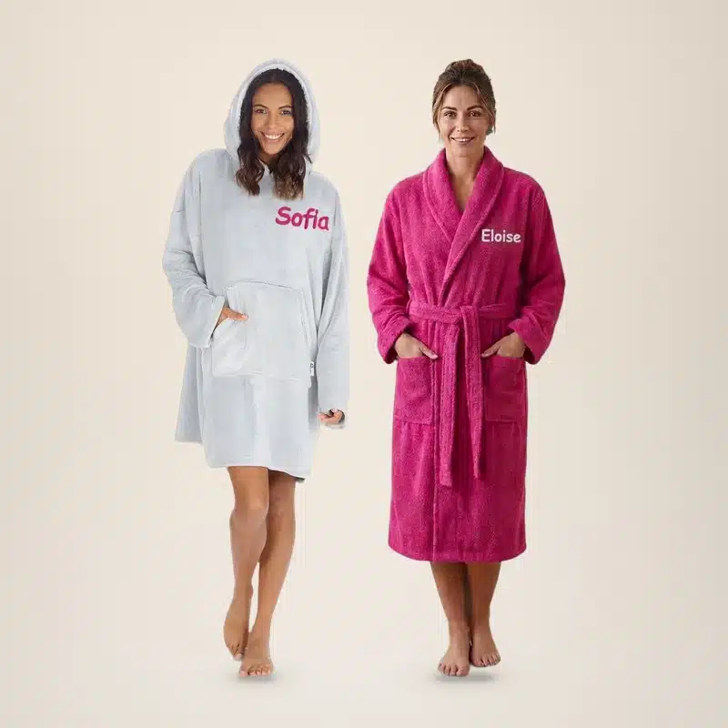 Woman in a grey personalised oversized hoodie embroidered Sofia next to a woman in a fuchsia towelling robe embroidered Eloise