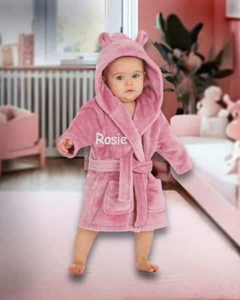 Baby in a dusky pink personalised hooded robe embroidered with Rosie
